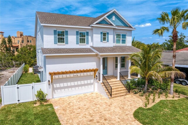 traditional-style house featuring a gate, decorative driveway, covered porch, an attached garage, and stucco siding