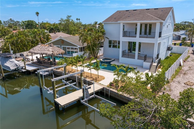 dock area with boat lift, a fenced backyard, a balcony, and a patio area
