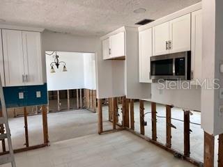 kitchen featuring white cabinetry, stainless steel microwave, and a textured ceiling