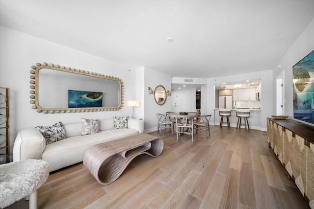 living area with visible vents, baseboards, and wood finished floors