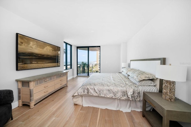 bedroom with expansive windows, access to outside, baseboards, and light wood-style flooring