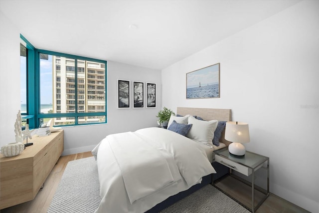 bedroom with a water view, baseboards, and wood finished floors