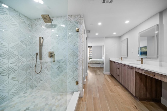 bathroom with double vanity, wood finished floors, walk in shower, recessed lighting, and a sink