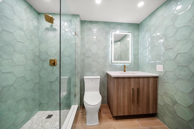 full bath featuring walk in shower, vanity, toilet, tile walls, and wood finished floors