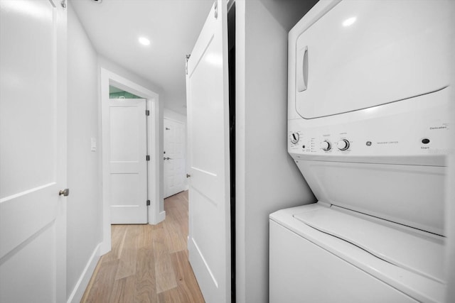 laundry area featuring recessed lighting, baseboards, stacked washer / dryer, and light wood-style floors