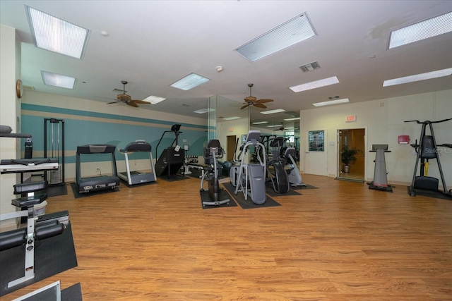 gym with a ceiling fan, visible vents, and light wood finished floors