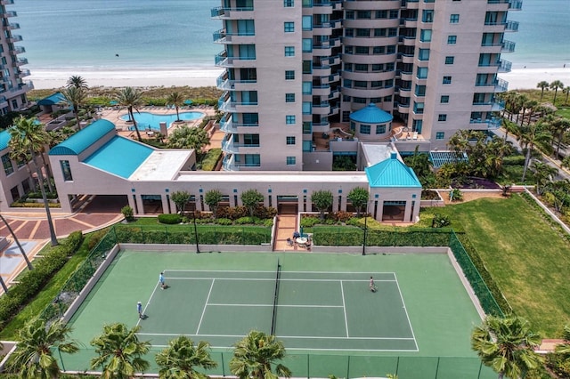 view of tennis court featuring a view of the beach and a water view