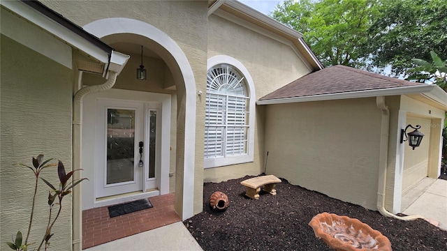 property entrance featuring brick siding, roof with shingles, and stucco siding
