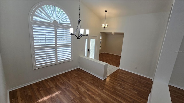 unfurnished dining area featuring baseboards, dark wood finished floors, a chandelier, and vaulted ceiling