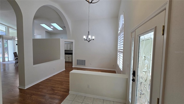 foyer with a chandelier, visible vents, a wealth of natural light, and wood finished floors