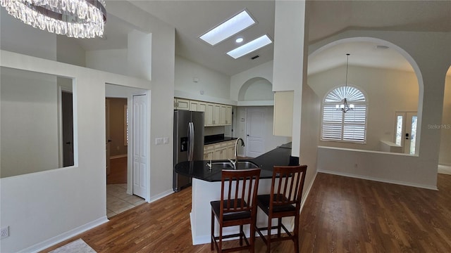 dining room with arched walkways, baseboards, wood finished floors, and a notable chandelier