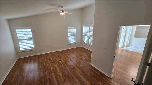 empty room featuring baseboards, ceiling fan, high vaulted ceiling, and wood finished floors
