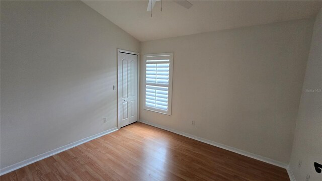 unfurnished room featuring ceiling fan, baseboards, lofted ceiling, and light wood-type flooring