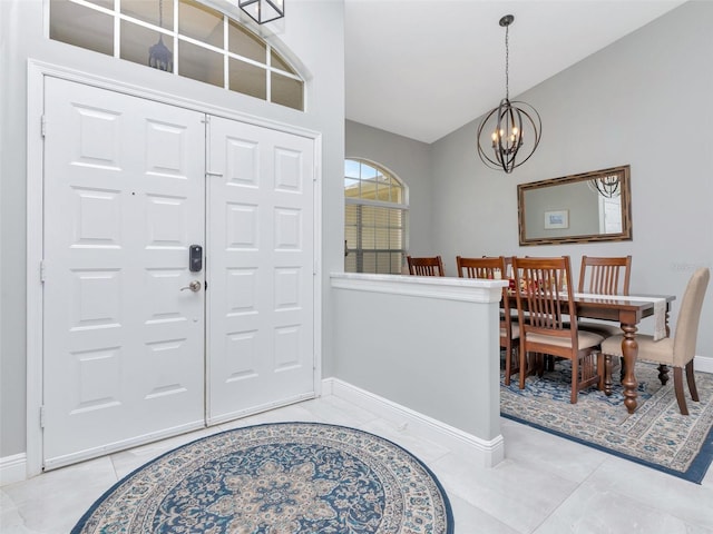 entryway featuring baseboards, high vaulted ceiling, light tile patterned floors, and an inviting chandelier