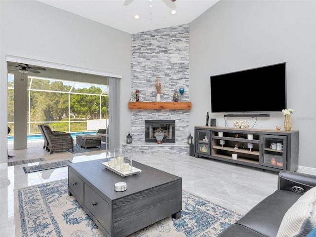living area featuring ceiling fan, a stone fireplace, and high vaulted ceiling