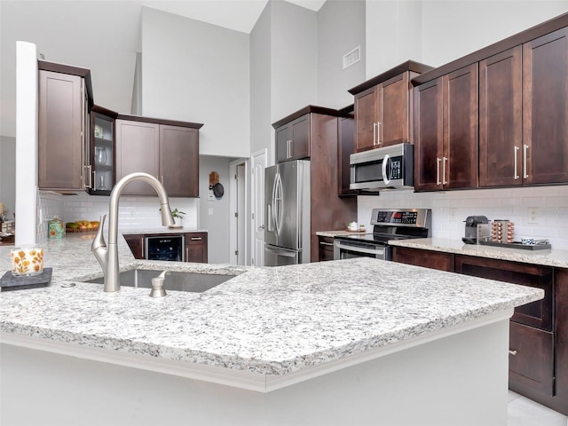 kitchen with appliances with stainless steel finishes, visible vents, light stone countertops, and a sink