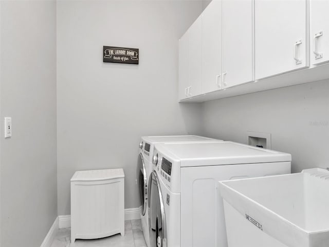 washroom with a sink, cabinet space, marble finish floor, baseboards, and washer and dryer
