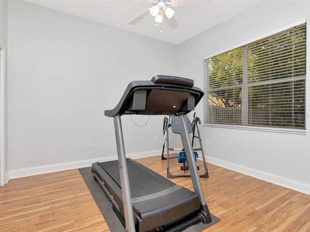 exercise room featuring ceiling fan, light wood-style floors, and baseboards