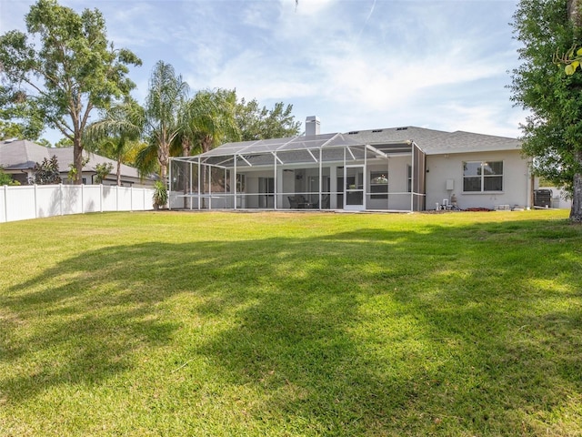 back of house with fence, a chimney, a yard, and a lanai
