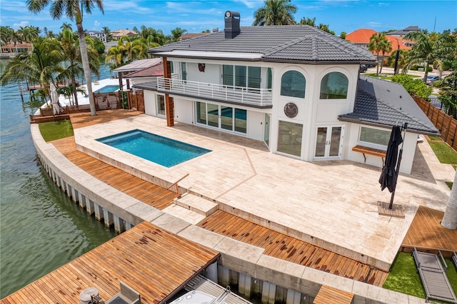 back of house with stucco siding, a water view, a patio, french doors, and a balcony