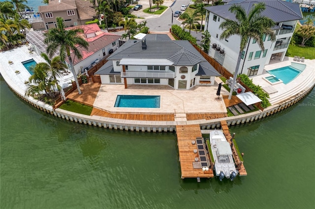 exterior space with a balcony, an in ground hot tub, and a water view