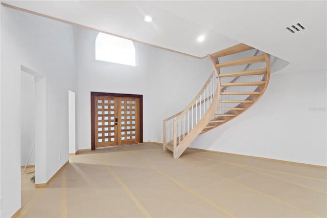 entryway featuring recessed lighting, a high ceiling, stairway, visible vents, and finished concrete flooring