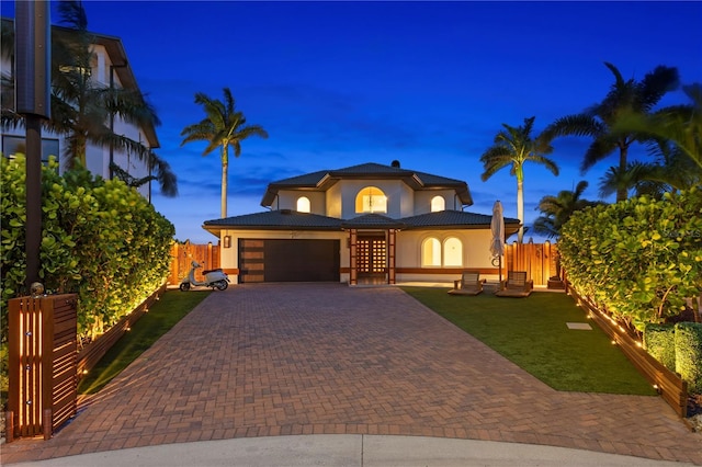 view of front of house with driveway, a tile roof, stucco siding, fence, and a garage