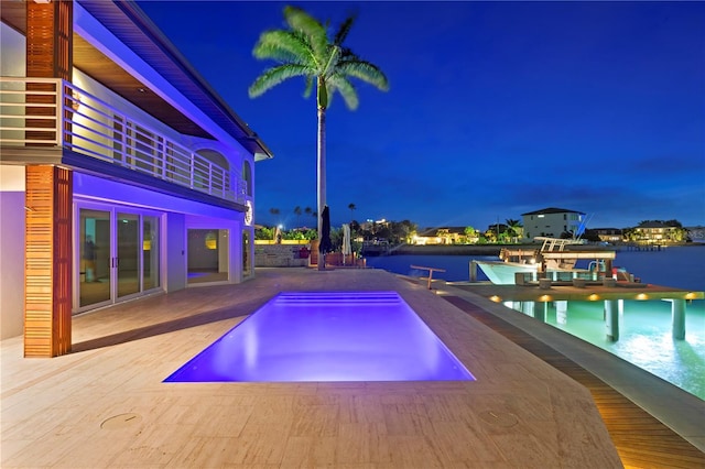 pool at night with an outdoor pool and a water view