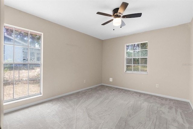 carpeted spare room featuring ceiling fan and baseboards