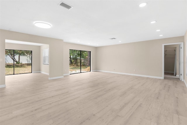 empty room with visible vents, light wood finished floors, and baseboards