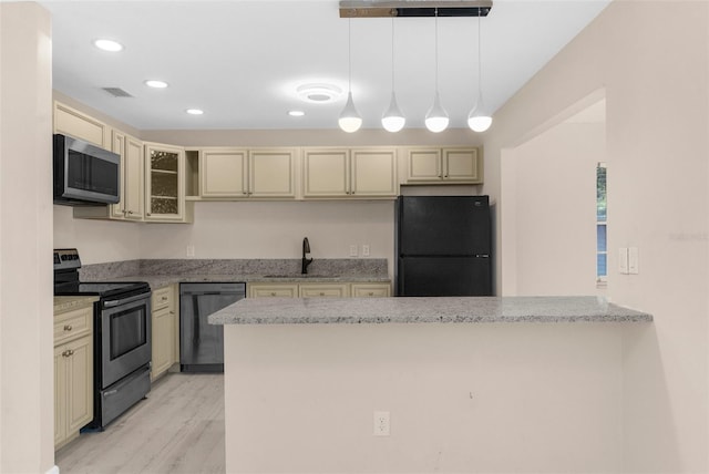 kitchen with a sink, glass insert cabinets, cream cabinetry, black appliances, and visible vents