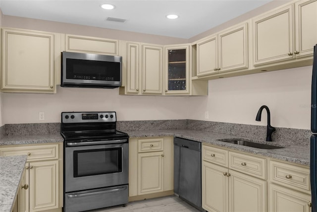 kitchen featuring a sink, cream cabinetry, visible vents, light stone counters, and appliances with stainless steel finishes