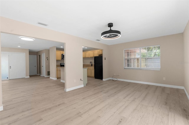 unfurnished living room with baseboards, visible vents, and light wood-type flooring
