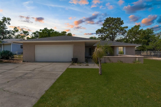 ranch-style home featuring fence, concrete driveway, a lawn, stucco siding, and a garage