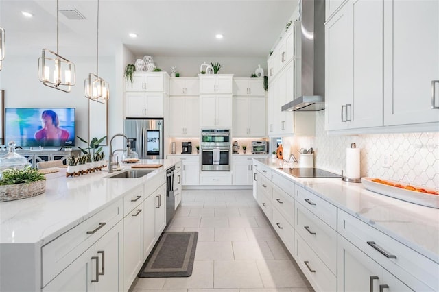 kitchen with wall chimney exhaust hood, a sink, stainless steel appliances, and decorative backsplash