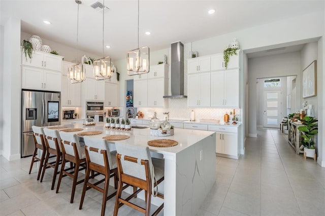 kitchen featuring tasteful backsplash, an inviting chandelier, stainless steel appliances, wall chimney range hood, and visible vents