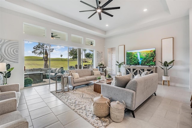 living room featuring ceiling fan, a raised ceiling, light tile patterned flooring, recessed lighting, and a towering ceiling
