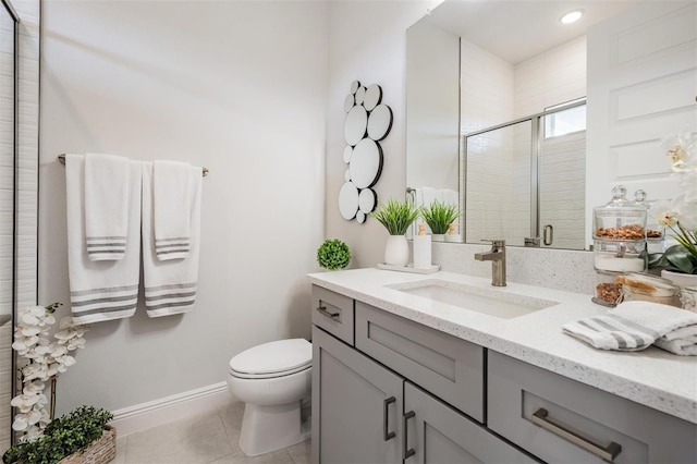 bathroom featuring vanity, tile patterned floors, toilet, a stall shower, and baseboards