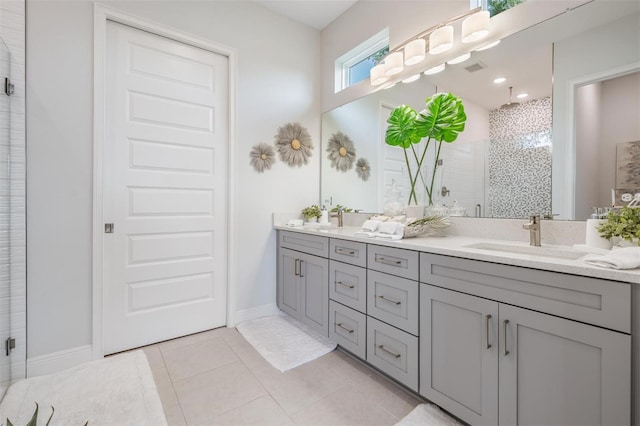 bathroom featuring a stall shower, double vanity, a sink, and tile patterned floors