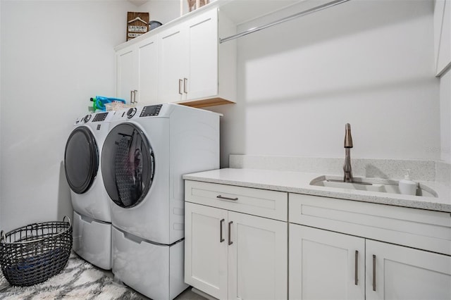 washroom with cabinet space, washing machine and clothes dryer, and a sink