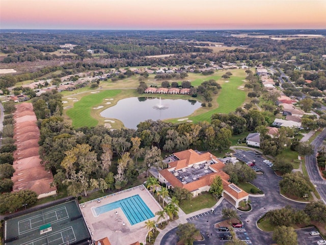 aerial view at dusk with a water view and view of golf course