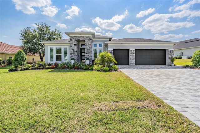 prairie-style house with a garage, decorative driveway, a front lawn, and stone siding