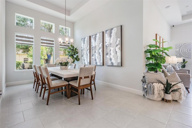 dining room featuring a towering ceiling, light tile patterned flooring, an inviting chandelier, and baseboards