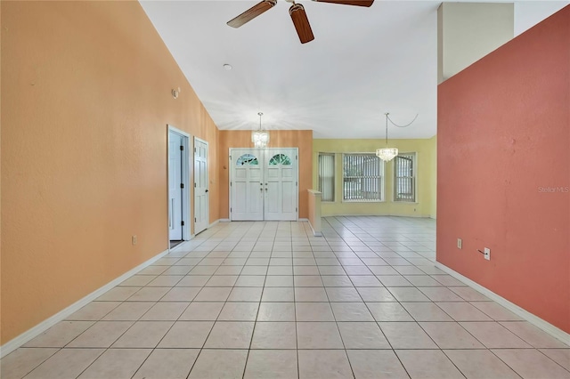 entryway with light tile patterned floors, baseboards, vaulted ceiling, and ceiling fan with notable chandelier