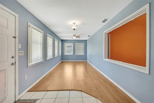 interior space featuring ceiling fan, baseboards, wood finished floors, and visible vents