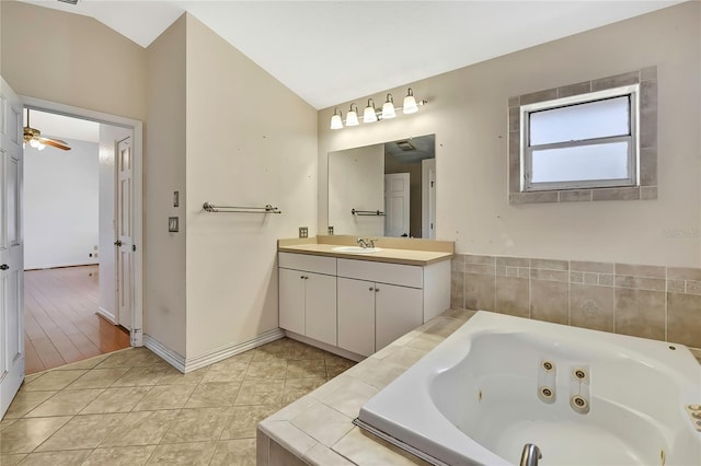 full bath with tile patterned flooring, ceiling fan, vanity, lofted ceiling, and a jetted tub