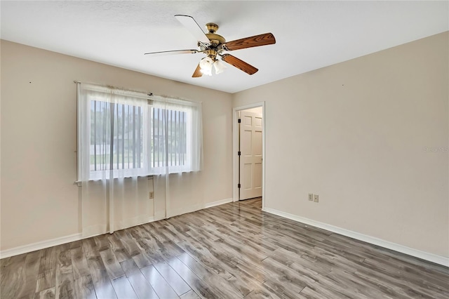 spare room featuring ceiling fan, wood finished floors, and baseboards