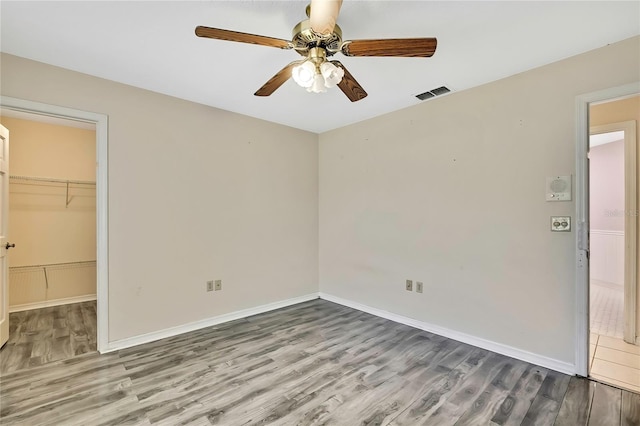 unfurnished bedroom with baseboards, visible vents, wood finished floors, and a spacious closet
