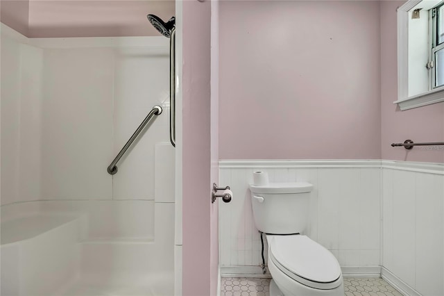 bathroom featuring walk in shower, toilet, wainscoting, and tile patterned flooring