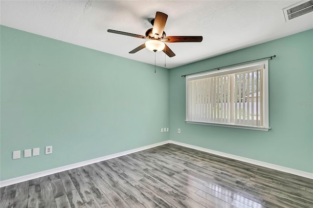 unfurnished room featuring baseboards, visible vents, wood finished floors, and a ceiling fan